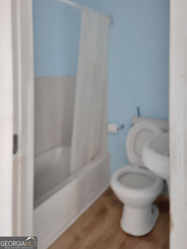 full bath with wood finished floors, shower / bath combination with curtain, and toilet