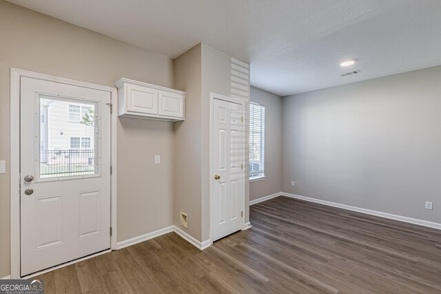 interior space with baseboards, visible vents, and dark wood-style floors