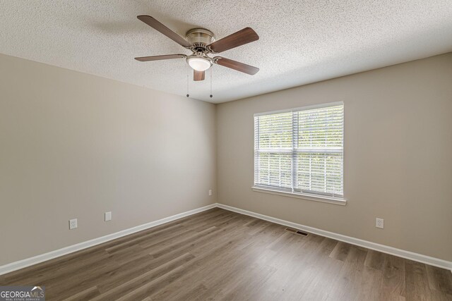 spare room with wood finished floors, a textured ceiling, baseboards, and ceiling fan