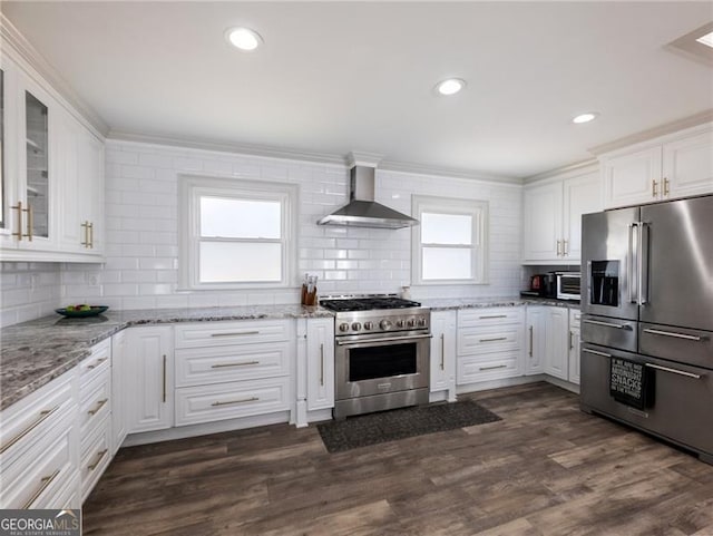 6041 Blackberry Ln, Buford, GA 30518 - kitchen featuring high end appliances, wall chimney exhaust hood, tasteful backsplash, white cabinets, and crown molding