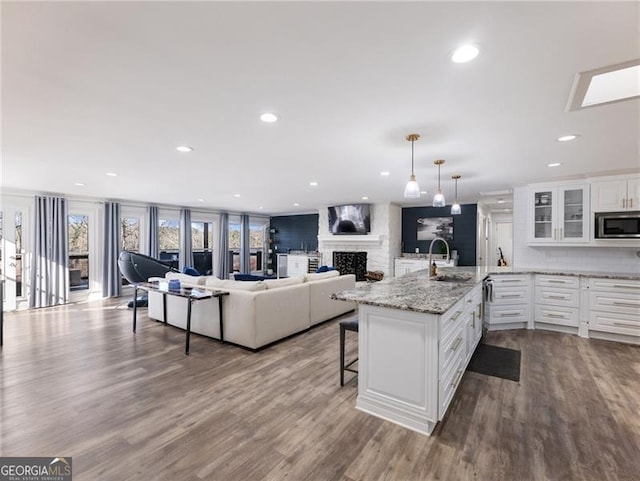 6041 Blackberry Ln, Buford, GA 30518 - kitchen with stainless steel microwave, a sink, a fireplace, a breakfast bar area, and glass insert cabinets