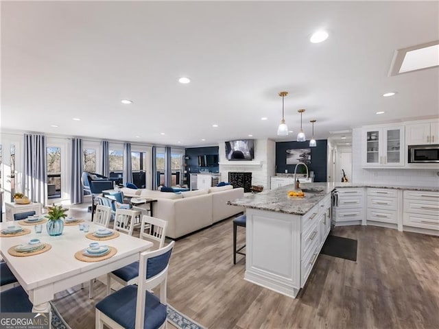 6041 Blackberry Ln, Buford, GA 30518 - kitchen featuring stainless steel microwave, a sink, glass insert cabinets, white cabinets, and a kitchen breakfast bar