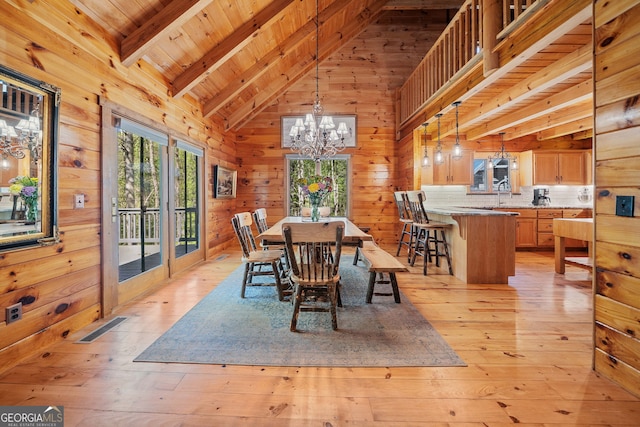 dining room featuring wood ceiling, wood walls, light wood-type flooring, a chandelier, and vaulted ceiling with beams