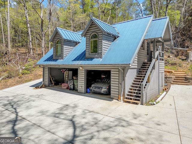 view of side of property with a detached garage, stairway, and metal roof