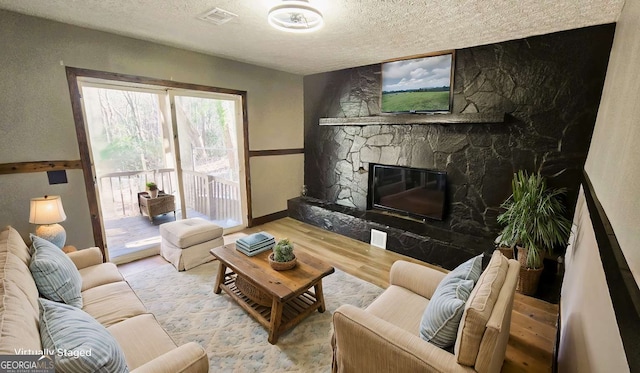 2172 Nancy Way, Loganville, GA 30052 - living room featuring a stone fireplace, wood finished floors, visible vents, and a textured ceiling