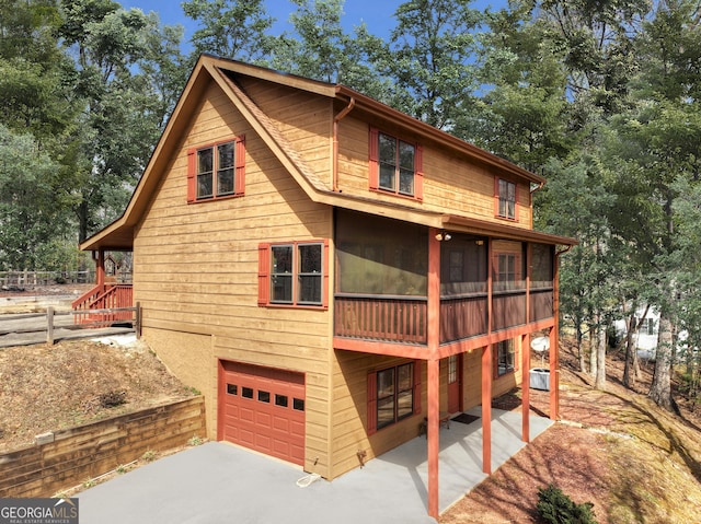 65 Weoka Ct, Ellijay, GA 30540 - back of house with an attached garage, concrete driveway, cooling unit, and a sunroom