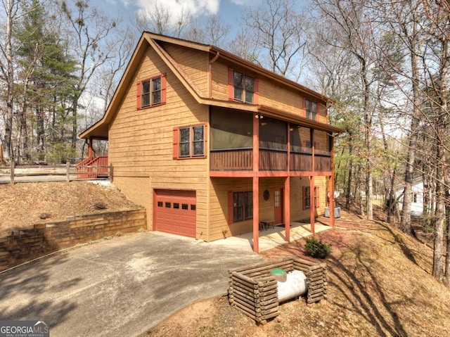 65 Weoka Ct, Ellijay, GA 30540 - back of house featuring an attached garage, driveway, and a sunroom