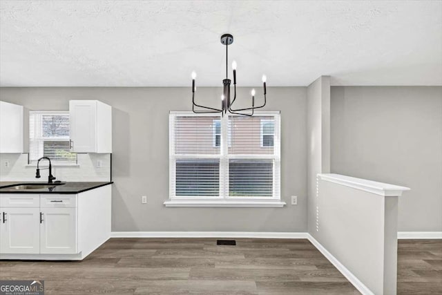 2478 Verbena Cir NW, Atlanta, GA 30314 - unfurnished dining area with baseboards, a chandelier, wood finished floors, a textured ceiling, and a sink