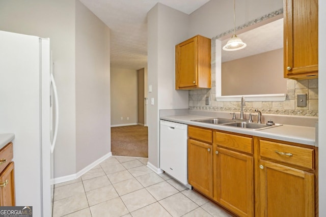 kitchen featuring backsplash, white appliances, light countertops, and a sink