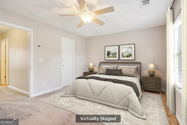 bedroom featuring visible vents, light colored carpet, baseboards, and ceiling fan