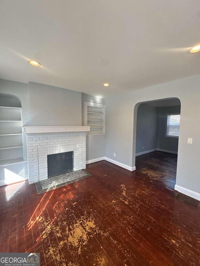 3426 Glenwood Rd, Decatur, GA 30032 - unfurnished living room featuring wood finished floors, built in features, arched walkways, and baseboards