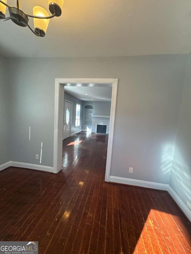 3426 Glenwood Rd, Decatur, GA 30032 - unfurnished room featuring a chandelier, a fireplace, baseboards, and wood-type flooring