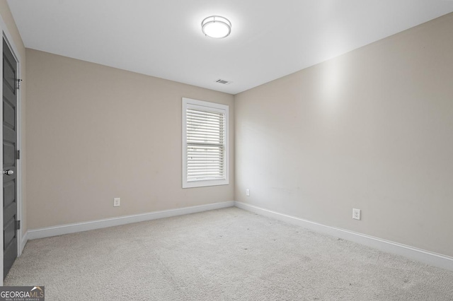 spare room featuring visible vents, light colored carpet, and baseboards