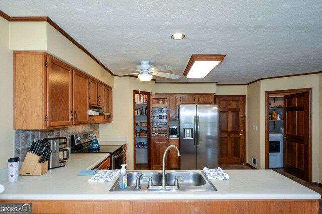 kitchen featuring a sink, light countertops, under cabinet range hood, appliances with stainless steel finishes, and washer / dryer