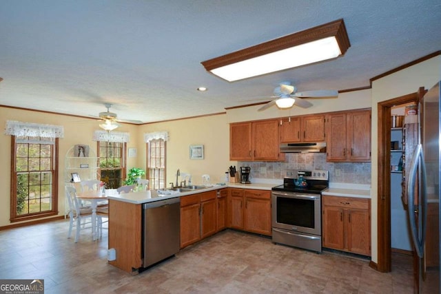 kitchen with stainless steel appliances, a peninsula, ornamental molding, and a ceiling fan