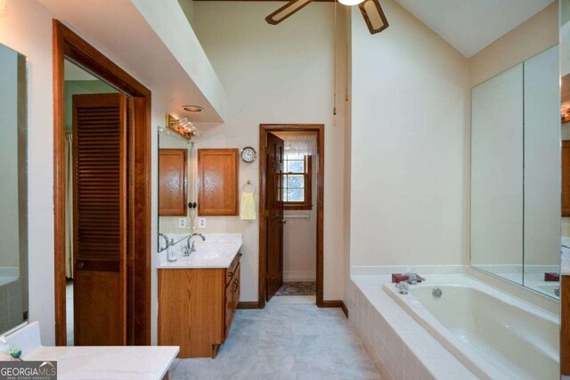 full bath featuring vaulted ceiling, a garden tub, vanity, ceiling fan, and tile patterned flooring
