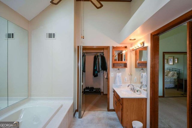 bathroom featuring lofted ceiling, visible vents, a garden tub, and vanity