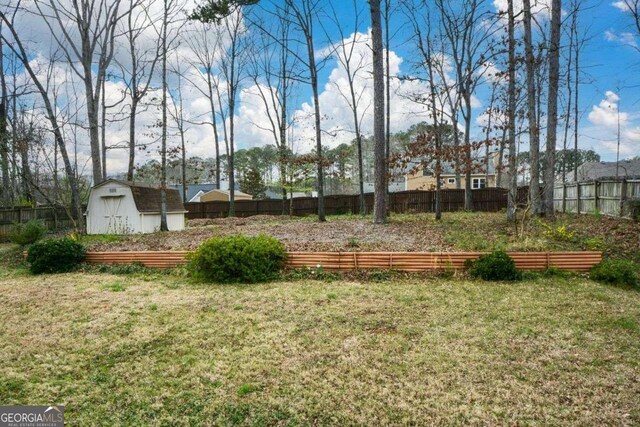 view of yard featuring fence, a storage unit, and an outbuilding