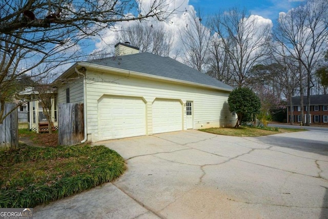 view of side of property with an attached garage, driveway, and a chimney