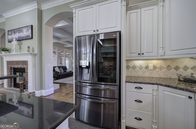 kitchen with coffered ceiling, crown molding, arched walkways, stainless steel fridge with ice dispenser, and backsplash