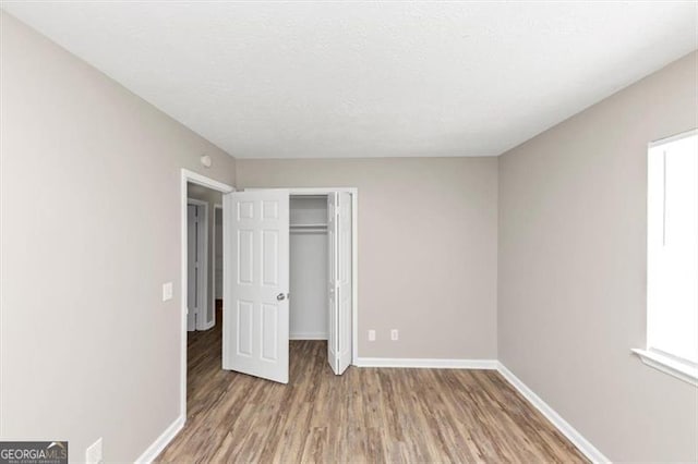 3671 Satellite Blvd, Ellenwood, GA 30294 - unfurnished bedroom featuring a closet, baseboards, a textured ceiling, and wood finished floors