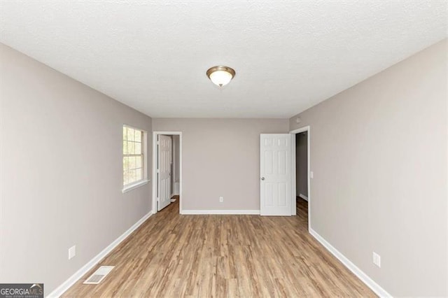 3671 Satellite Blvd, Ellenwood, GA 30294 - unfurnished room featuring light wood finished floors, visible vents, a textured ceiling, and baseboards