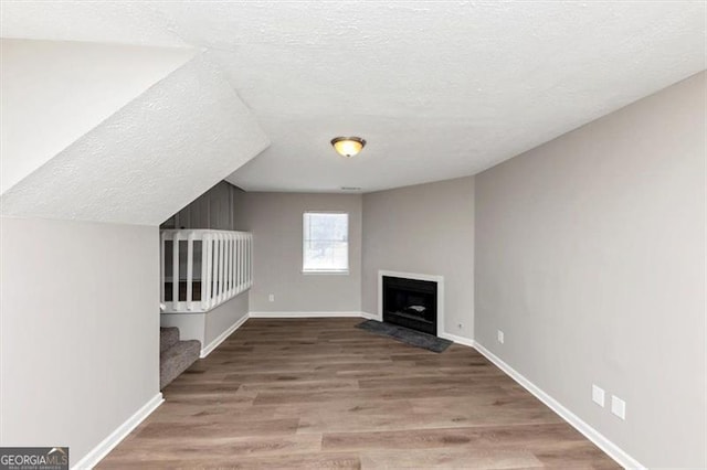 3671 Satellite Blvd, Ellenwood, GA 30294 - unfurnished living room featuring baseboards, a fireplace with flush hearth, a textured ceiling, and wood finished floors