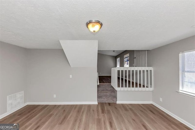 3671 Satellite Blvd, Ellenwood, GA 30294 - additional living space with visible vents, baseboards, a textured ceiling, and wood finished floors