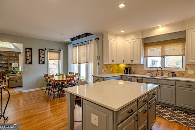5 Pembroke Ln, Cartersville, GA 30120 - kitchen featuring light wood finished floors, gray cabinetry, a kitchen island, decorative backsplash, and a sink