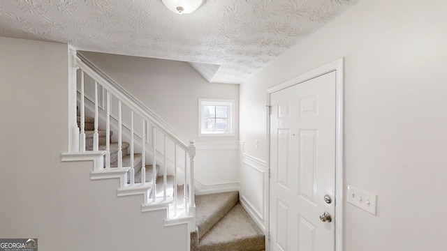 921 Dunagan Way, Lawrenceville, GA 30045 - foyer entrance featuring stairs, a textured ceiling, carpet floors, and a wainscoted wall