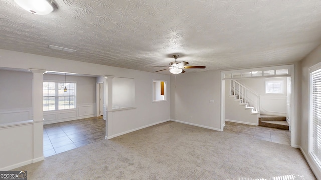 921 Dunagan Way, Lawrenceville, GA 30045 - carpeted empty room featuring stairway, ceiling fan, a textured ceiling, tile patterned floors, and ornate columns