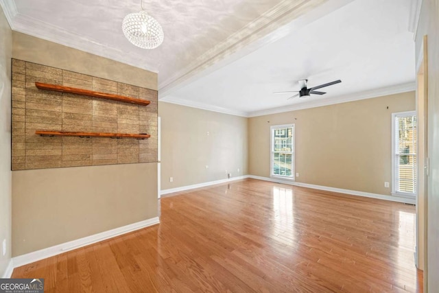 unfurnished living room with crown molding, ceiling fan with notable chandelier, light wood-style floors, and baseboards