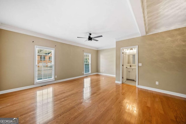 unfurnished bedroom featuring light wood finished floors, ensuite bathroom, crown molding, and baseboards