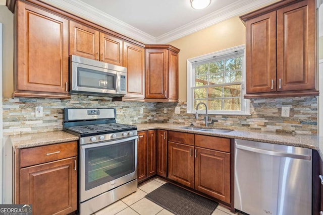 kitchen featuring a sink, stainless steel appliances, light stone countertops, and tasteful backsplash