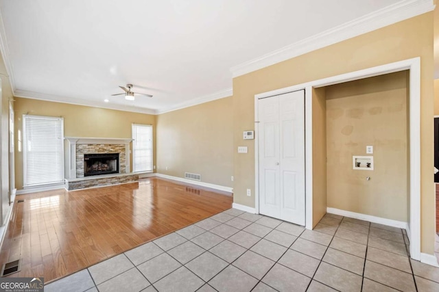 unfurnished living room with a ceiling fan, baseboards, visible vents, light tile patterned flooring, and ornamental molding