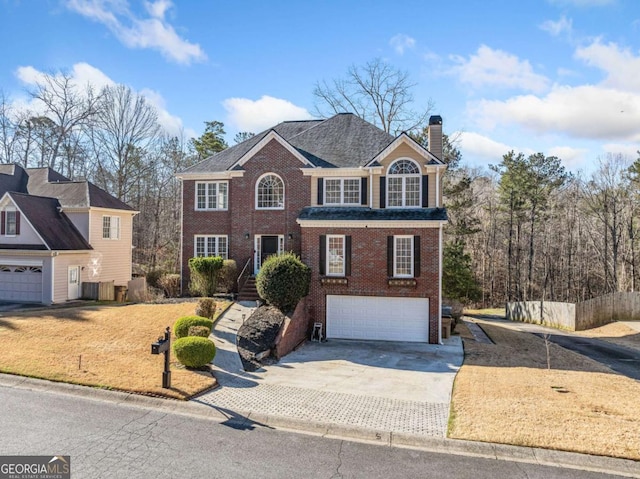 view of front of house with a garage, brick siding, driveway, and a chimney