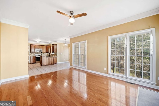 unfurnished living room with light wood finished floors, visible vents, baseboards, ceiling fan, and ornamental molding