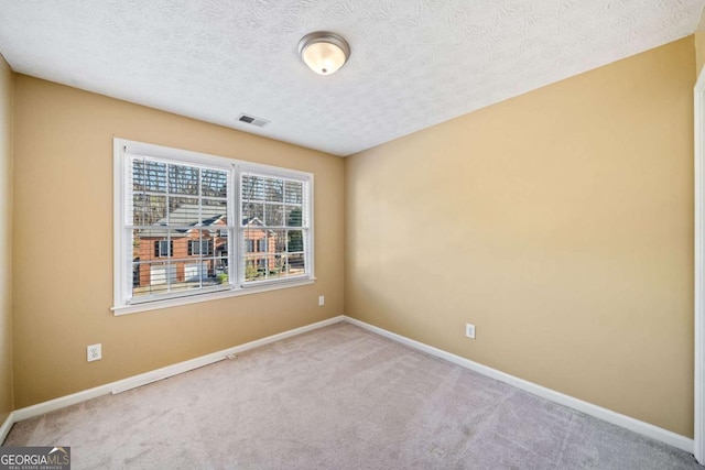 spare room with visible vents, baseboards, a textured ceiling, and carpet flooring