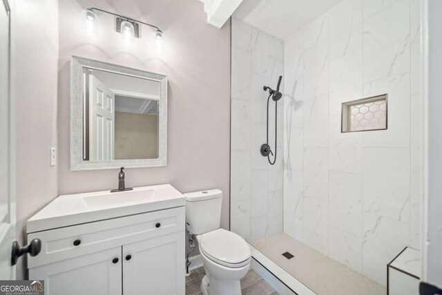 full bathroom with tiled shower, toilet, and vanity