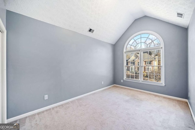 carpeted spare room with visible vents, lofted ceiling, a textured ceiling, and baseboards