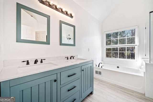 full bathroom with lofted ceiling, a garden tub, double vanity, and a sink