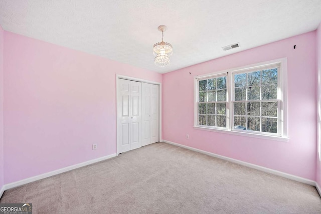 unfurnished bedroom with visible vents, baseboards, a closet, and carpet flooring