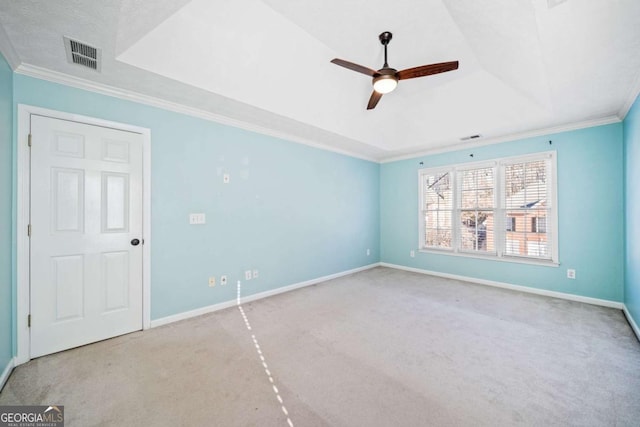 carpeted spare room featuring a tray ceiling, ornamental molding, visible vents, and ceiling fan