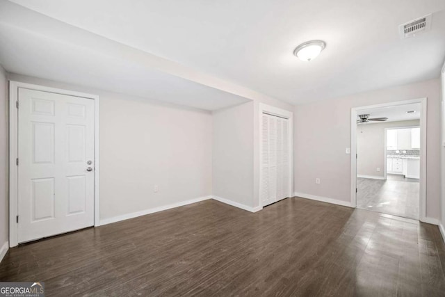empty room with visible vents, a ceiling fan, baseboards, and dark wood-style flooring