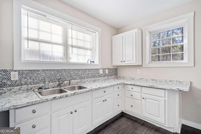 kitchen featuring dark wood-style floors, white cabinets, a healthy amount of sunlight, and a sink