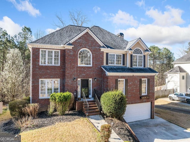 colonial inspired home with fence, a chimney, concrete driveway, a garage, and brick siding