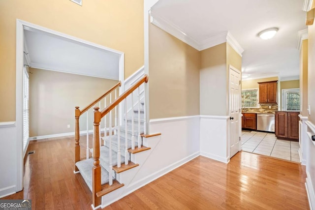 stairway with baseboards, wood finished floors, and ornamental molding