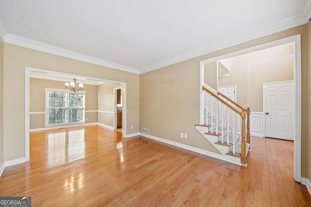 empty room featuring light wood finished floors, baseboards, stairs, ornamental molding, and a notable chandelier