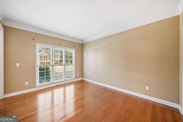 spare room with visible vents, baseboards, ornamental molding, and light wood finished floors