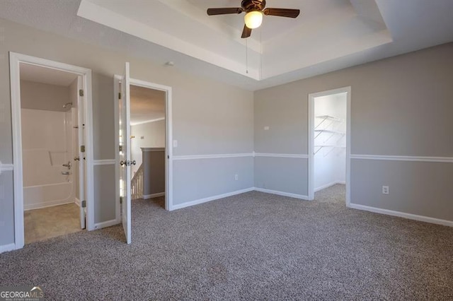 6251 Lamp Post Pl, Atlanta, GA 30349 - unfurnished bedroom with a tray ceiling, carpet, a walk in closet, and ensuite bathroom